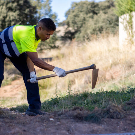A young Hispanic male worker plowing soil in a park
